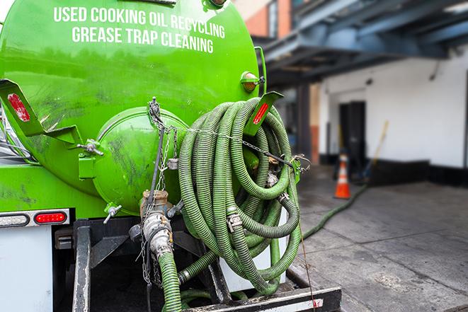 worker pumping grease trap at commercial kitchen in Arlington, MA